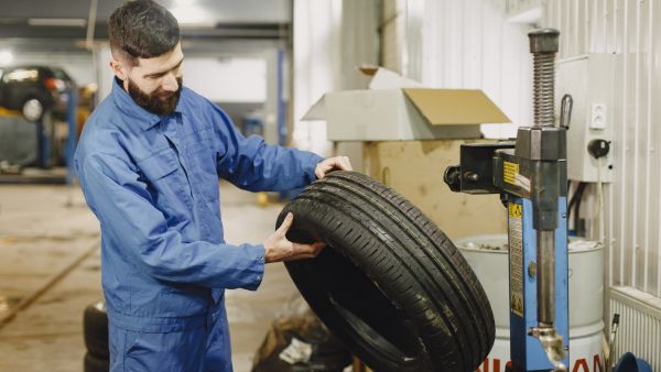 Mecânico analisando estado do pneu do carro na manutenção preventiva