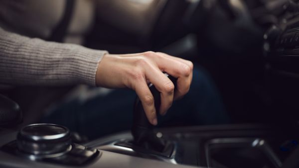 Mulher dirigindo com mão sobre o cambio manual do carro