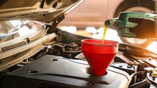 Pessoa colocando óleo do carro através de um funil