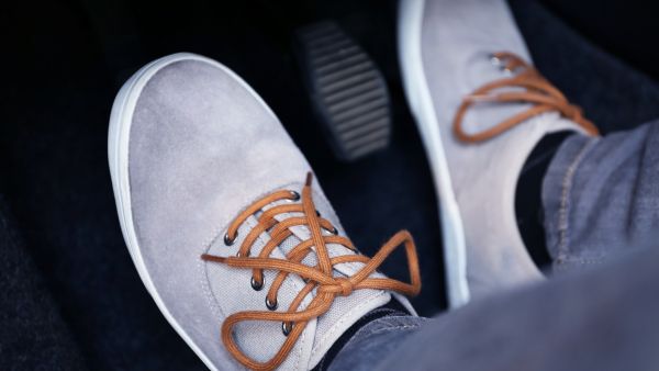 Pessoa com pés na embreagem e acelerador do carro