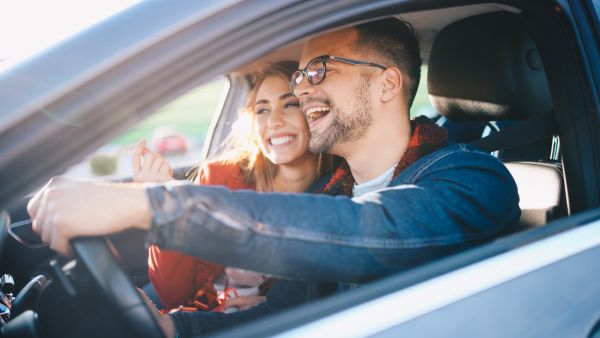 Casal feliz dirigindo com marcha apropriada à velocidade do veículo