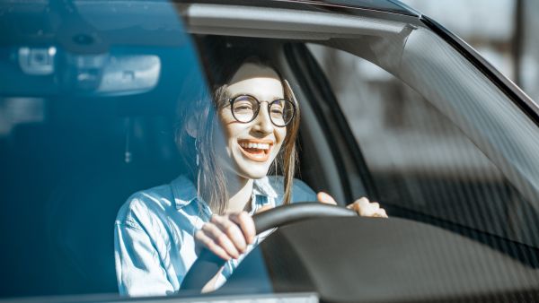 Mulher feliz dirigindo após passar por manutenção de carro elétrico