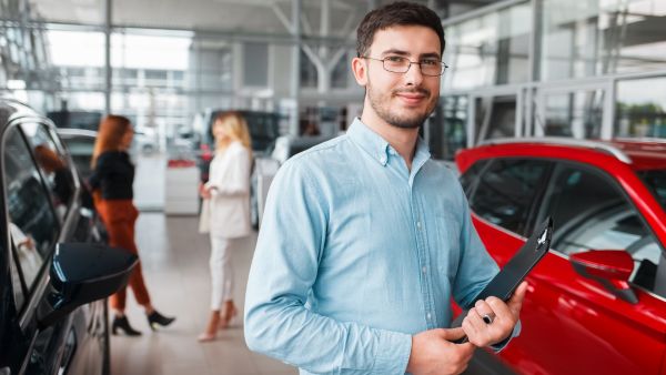 Colaborador de revendedora de carros usados com prancheta nas mãos