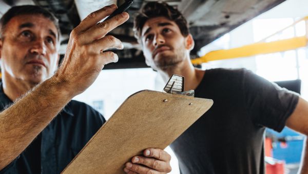 Mecânicos avaliando alinhamento e balanceamento de rodas do carro