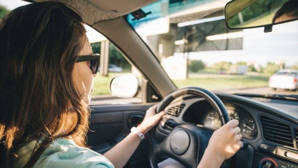 Mulher dirigindo com conforto e segurança devido a suspensão do carro