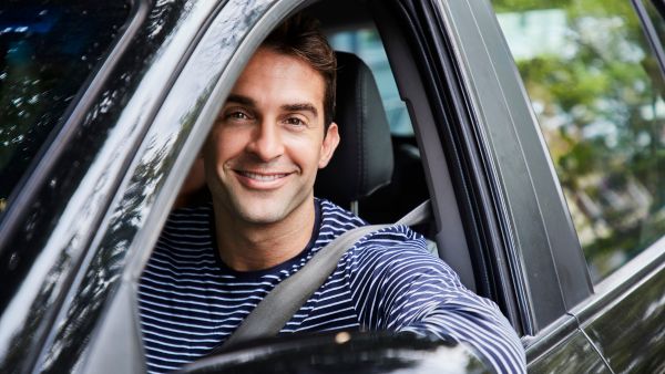 Homem dirigindo feliz após efetuar troca de óleo do câmbio automático do carro