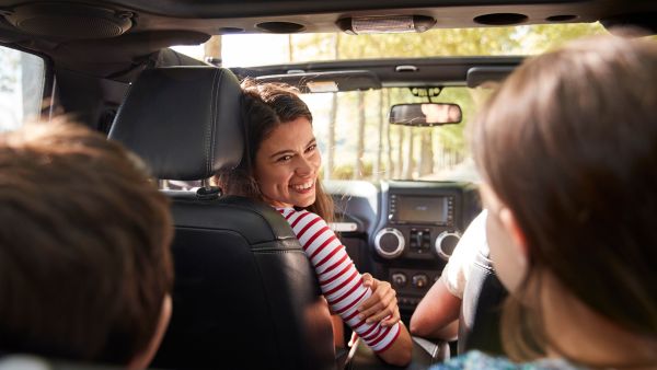 Mulher brincando com filhos antes de começar a dirigir carro em perfeitas condições