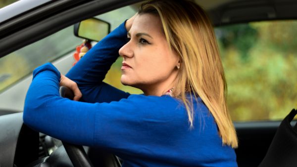 Mulher com carro estacionado preocupada com superaquecimento do câmbio automático