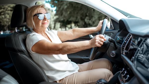 Mulher idosa dirigindo tranquilamente com as duas mãos no volante