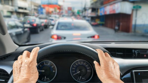 Pessoa da terceira idade dirigindo carro de idoso automático em tráfego intenso