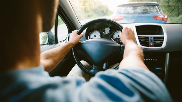 Homem dirigindo carro manual próximo a outro veículo na estrada