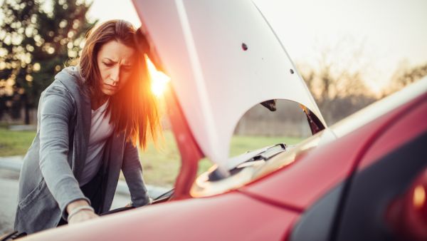 Mulher na estrada com problemas no carro por falta de manutenção do câmbio automático