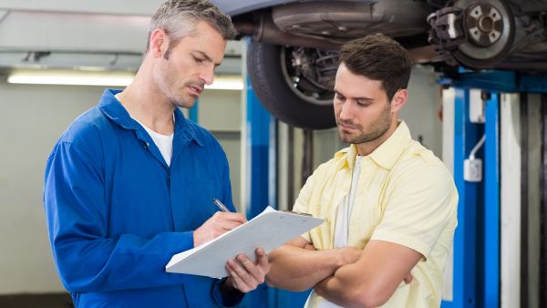 Condutor ouvindo do mecânico quais itens serão checados nas revisões preventivas do seu carro