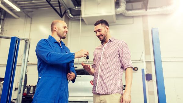 Homem feliz ao buscar o carro que passou por revisões preventivas em oficina de confiança