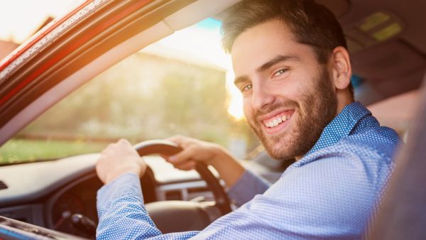 Homem sorrindo enquanto dirige carro automático com tranquilidade