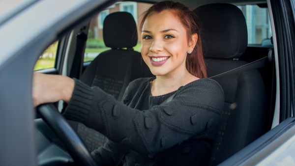 Mulher feliz após dirigir aplicando práticas de direção defensiva