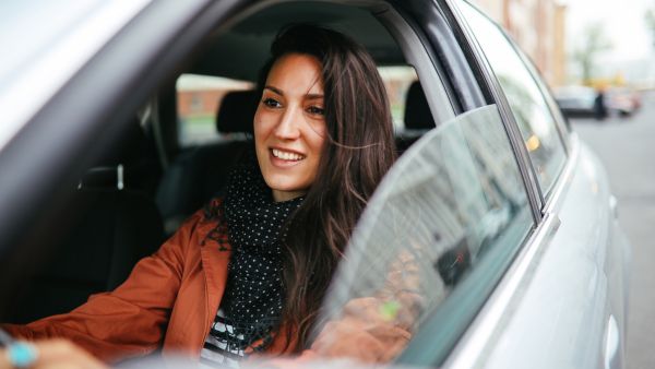 Mulher feliz dirigindo carro evitando maus hábitos de condução