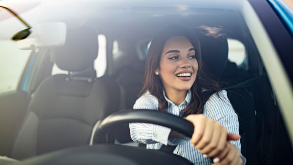 Mulher feliz dirigindo novo automóvel após vender o antigo sem deixar desvalorizar