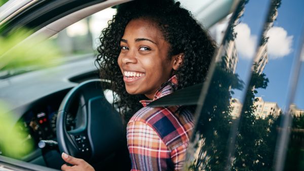 Mulher feliz ao dirigir carro de última geração