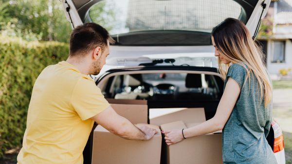 Casal colocando caixas no porta malas respeitando limite de excesso de peso no carro