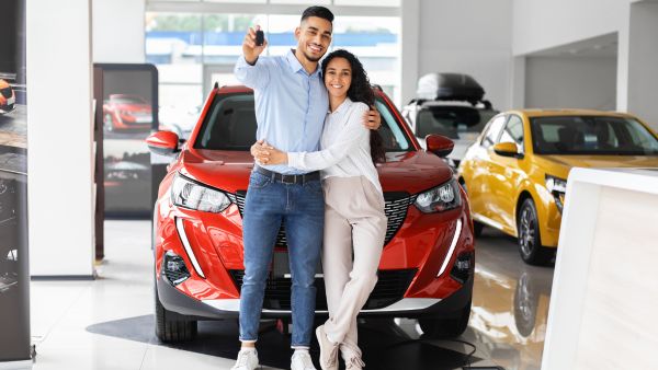 Casal feliz na concessionária depois de fechar a compra de carro novo