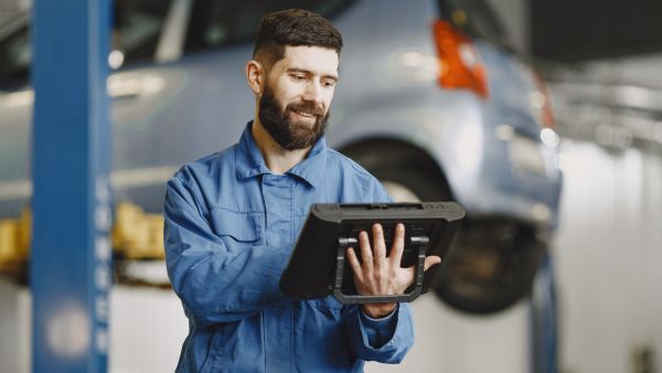 Mecânico avaliando estado de diferentes peças do carro utilizando tablet