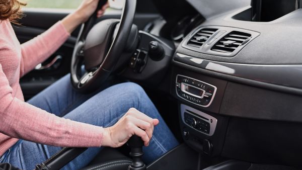 Mulher dirigindo carro com câmbio manual