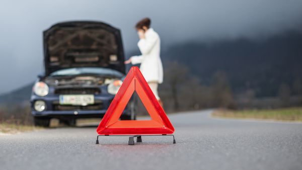 Mulher ligando para seguro após carro dar problema na estrada